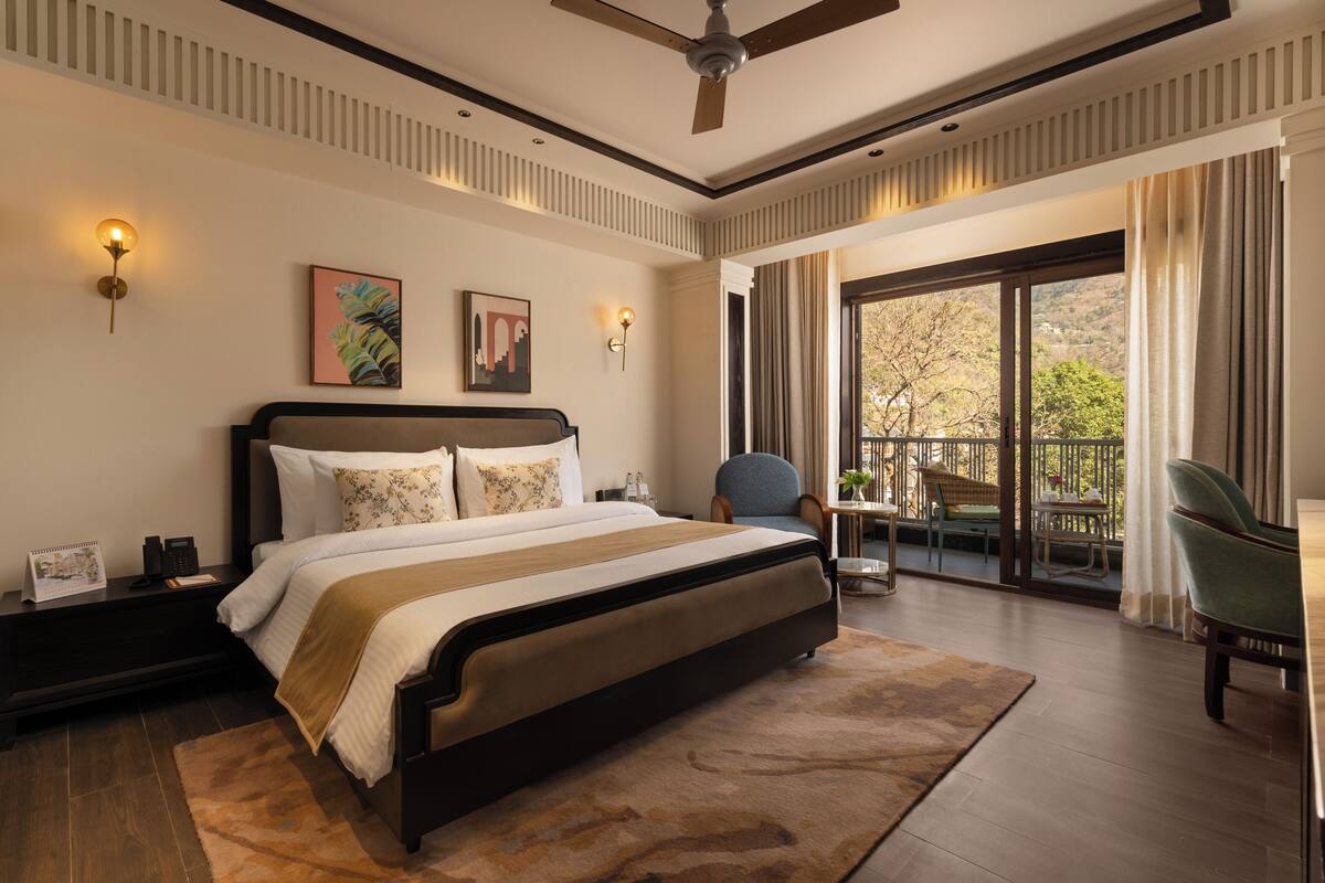 A spacious bedroom with a large bed, a ceiling fan, and a balcony with outdoor seating.
