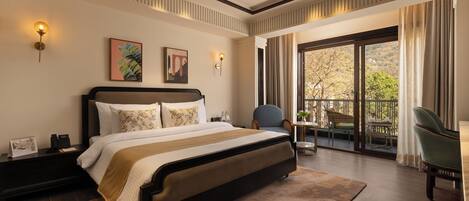 A spacious bedroom with a large bed, a ceiling fan, and a balcony with outdoor seating.
