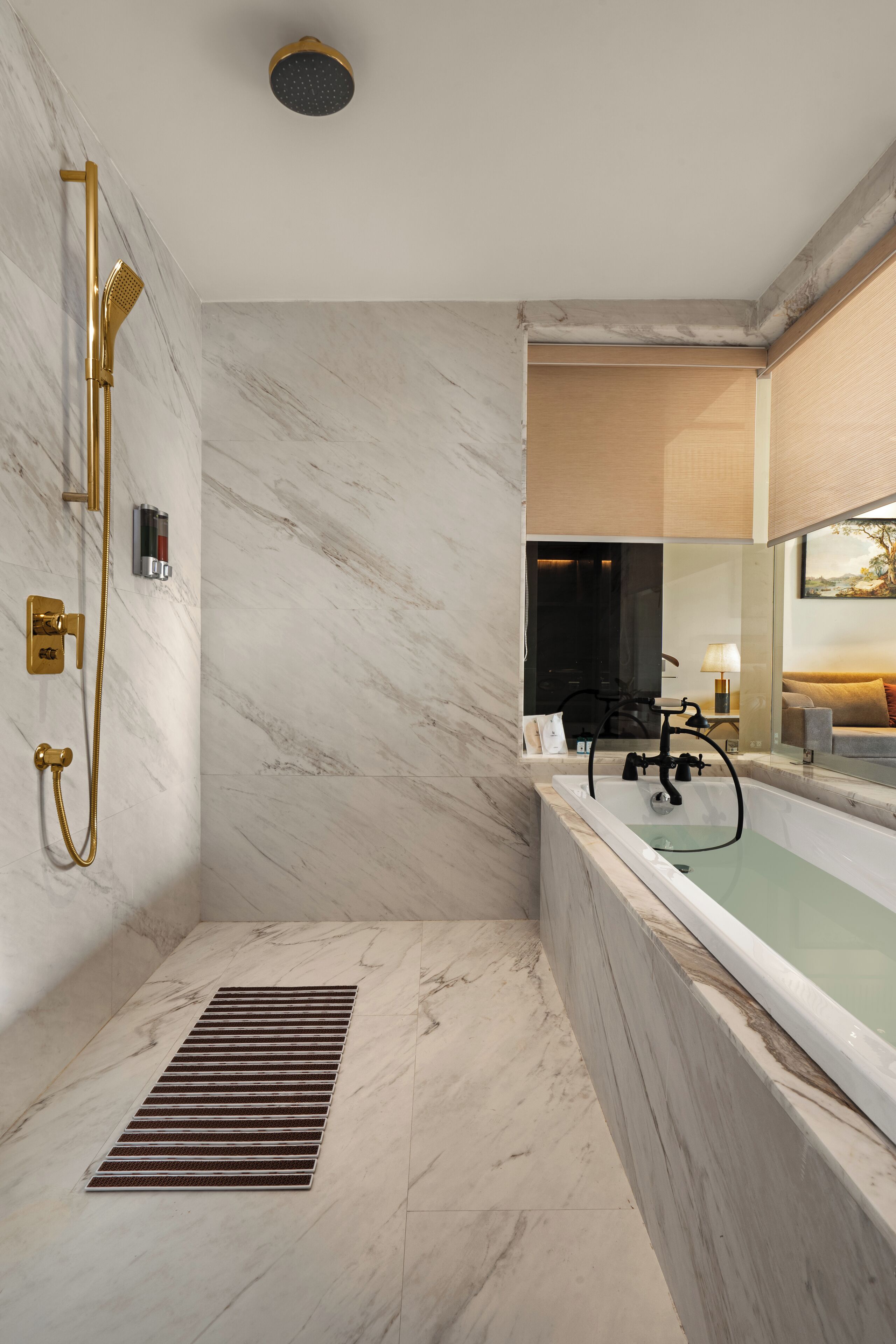 A modern bathroom with a marble floor, a freestanding bathtub, and a gold shower system.