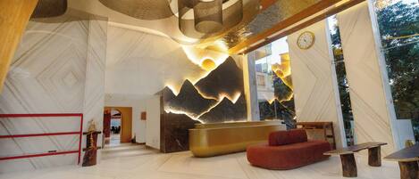 A spacious lobby with a reception desk, a red sofa, and a unique ceiling design.