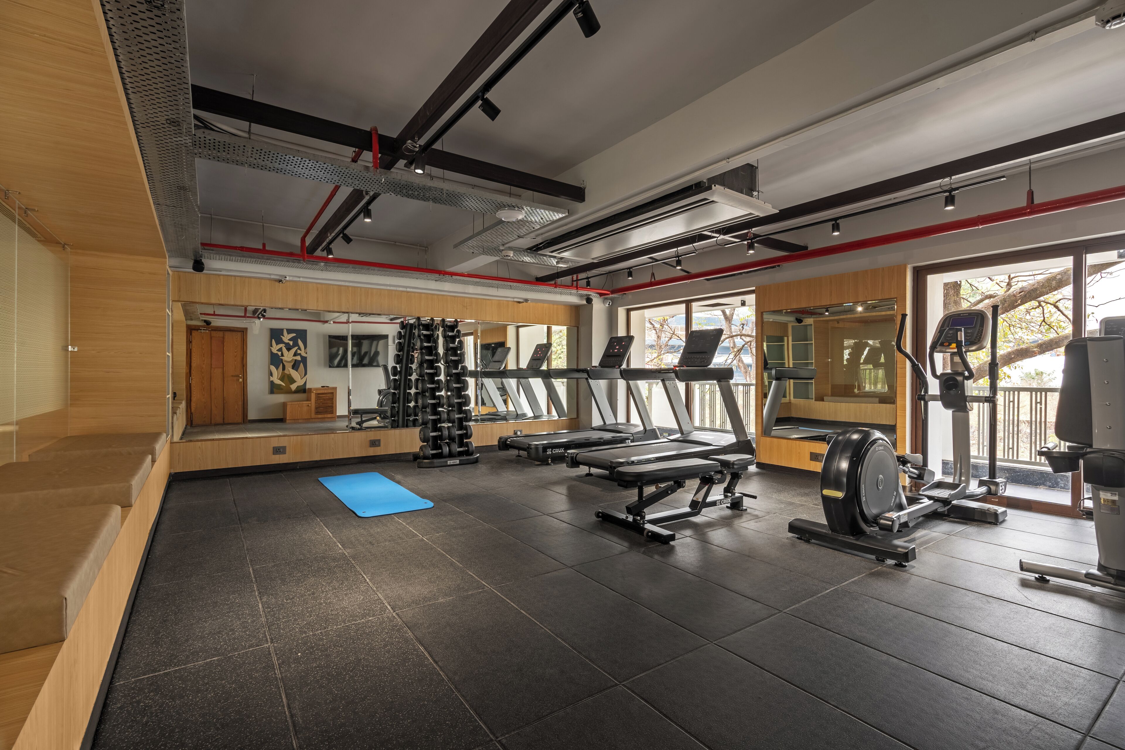A gym with treadmills, weight machines, and a mirror wall.