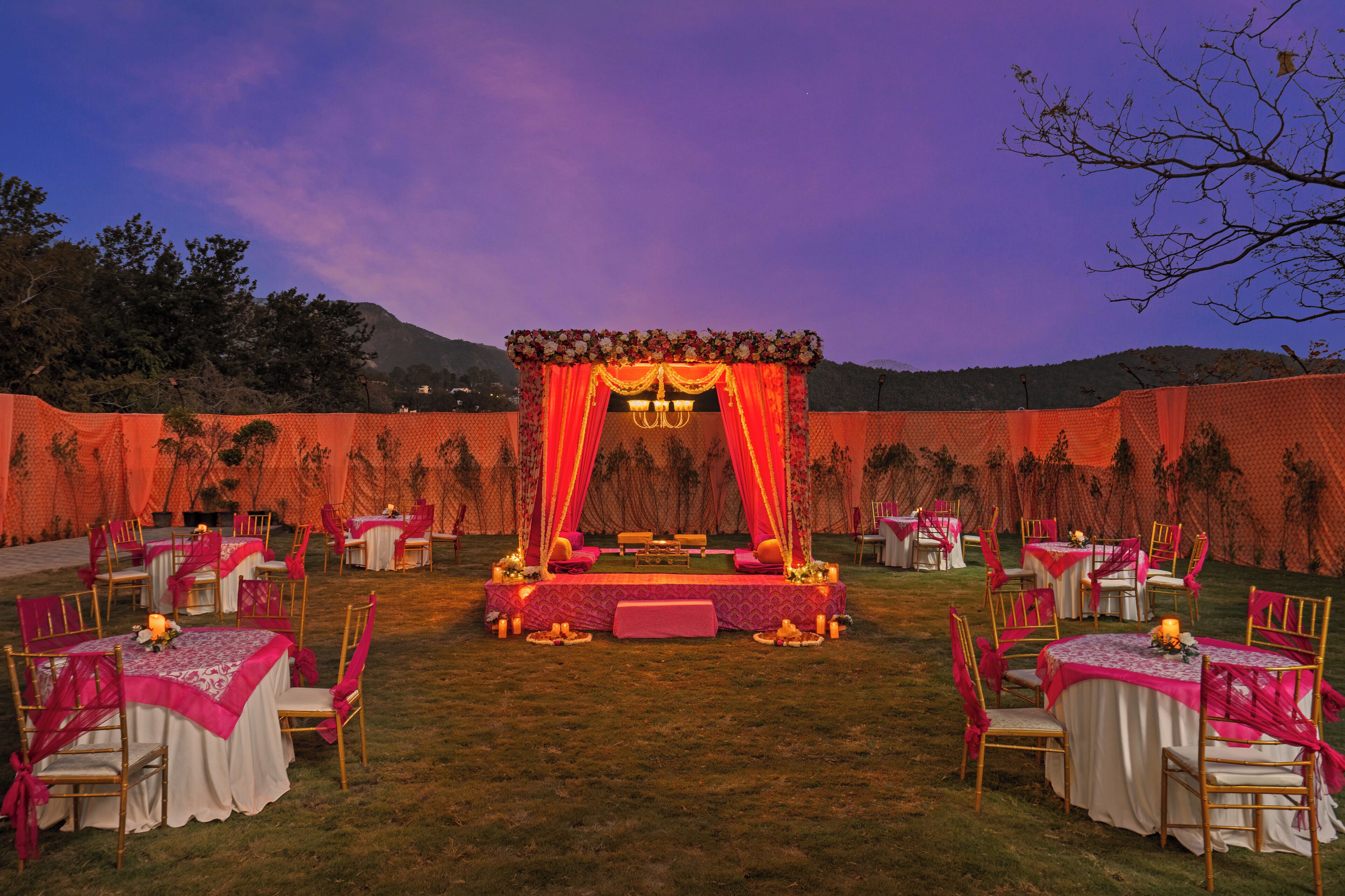 An outdoor wedding setup with a stage, tables, and chairs arranged for guests.