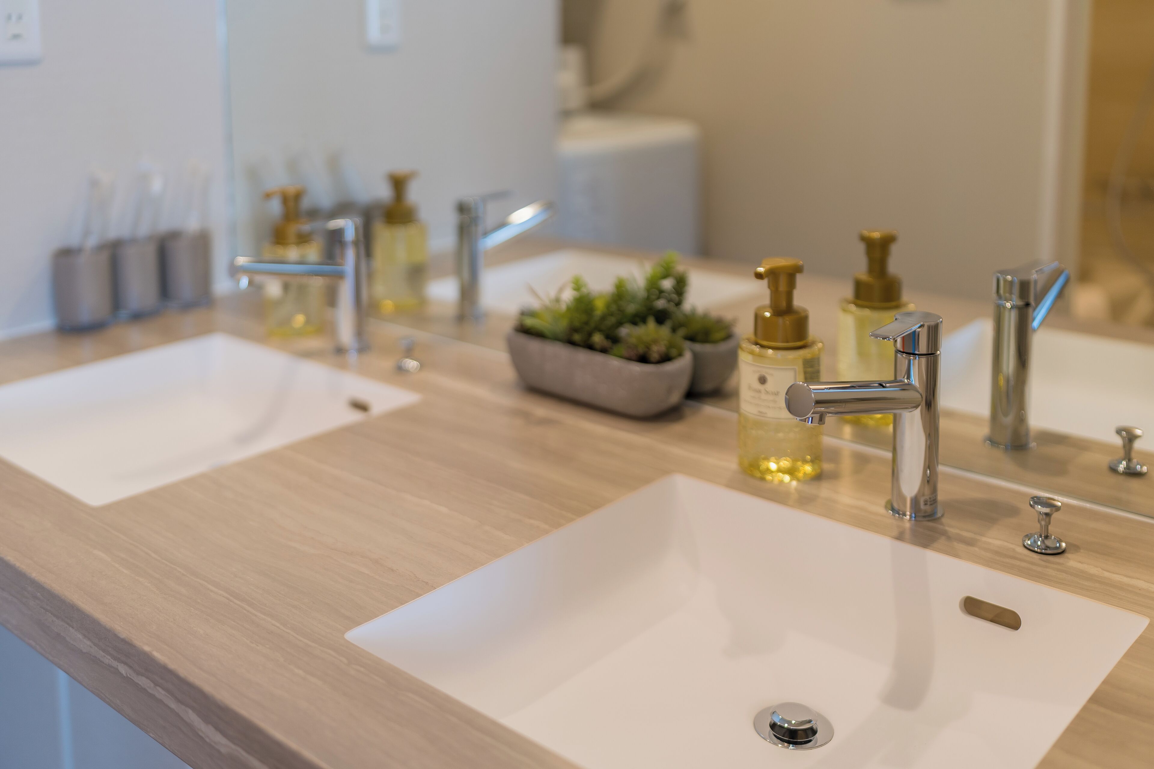 Casa de banho com duas pias, espelho e vários produtos de higiene pessoal.