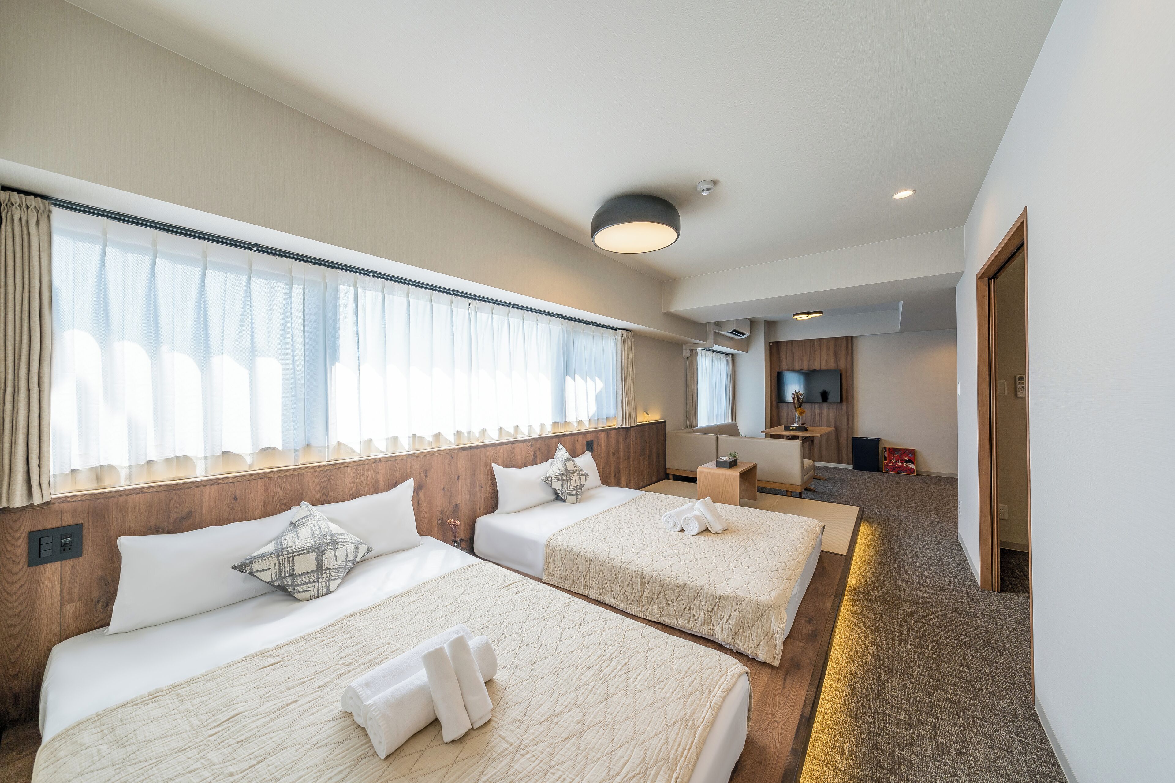 A hotel room with two beds, a TV, and a desk.