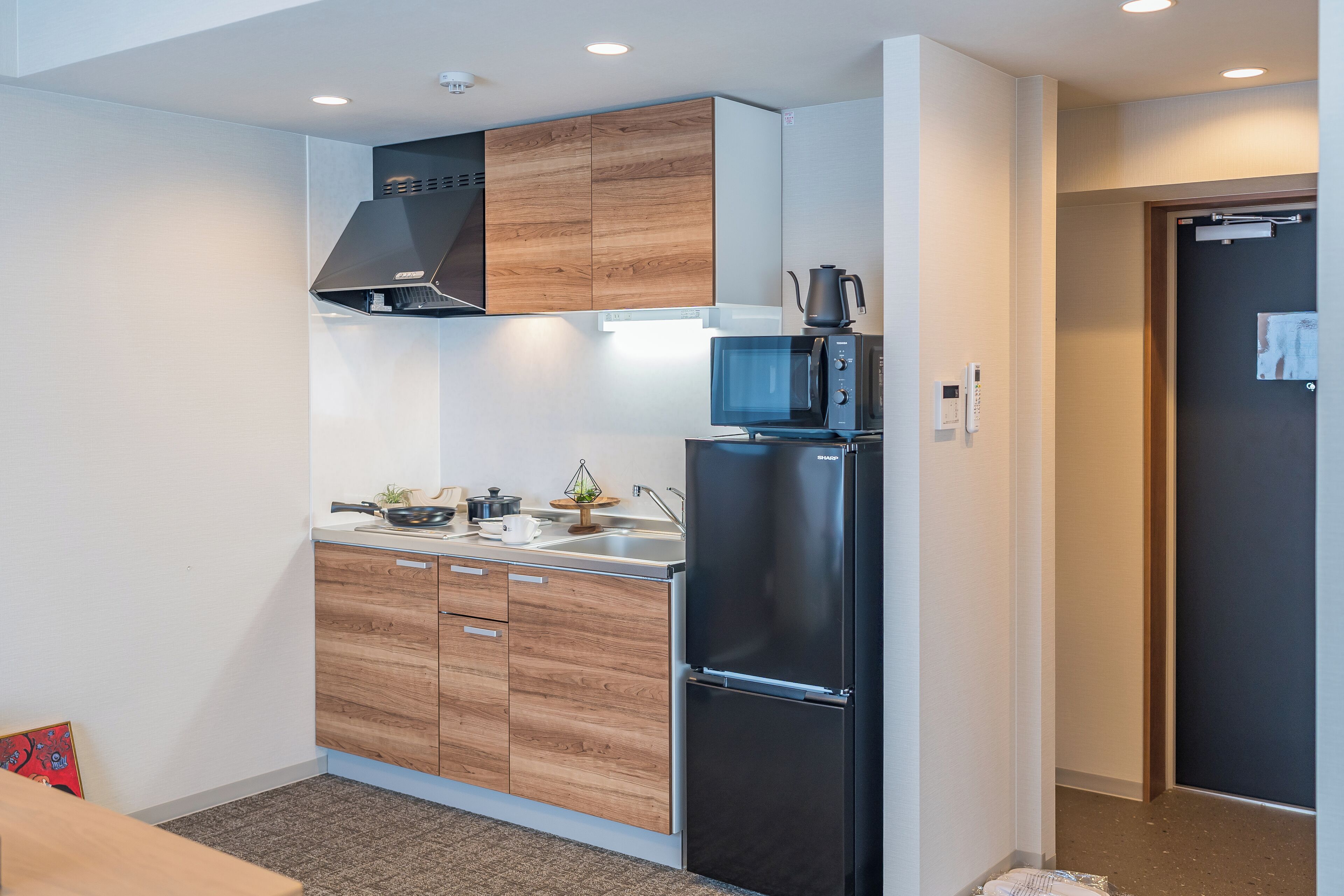 A modern kitchen with wooden cabinets, a black refrigerator, and a microwave.