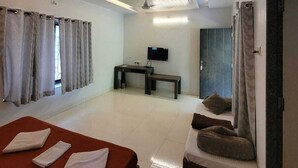 Ein modernes Hotelzimmer mit Bett, Schreibtisch, Fernseher und einer Sitzecke.