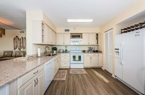 A compact kitchen with white cabinetry, a built-in oven, a microwave, and a refrigerator.