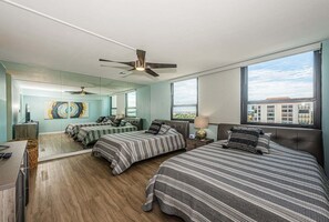 Hotelkamer met twee bedden, een plafondventilator, een groot raam met uitzicht op de stad en een modern design.