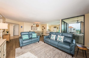 A spacious living area with two leather sofas, a dining table, and a kitchen in the background. - 2BR waterfront condo with balcony, pool, hot tub, and beachy views. (St. Petersburg)