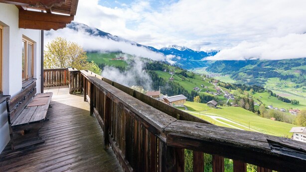 Ein Holzbalkon mit Blick auf ein Tal und Berge.