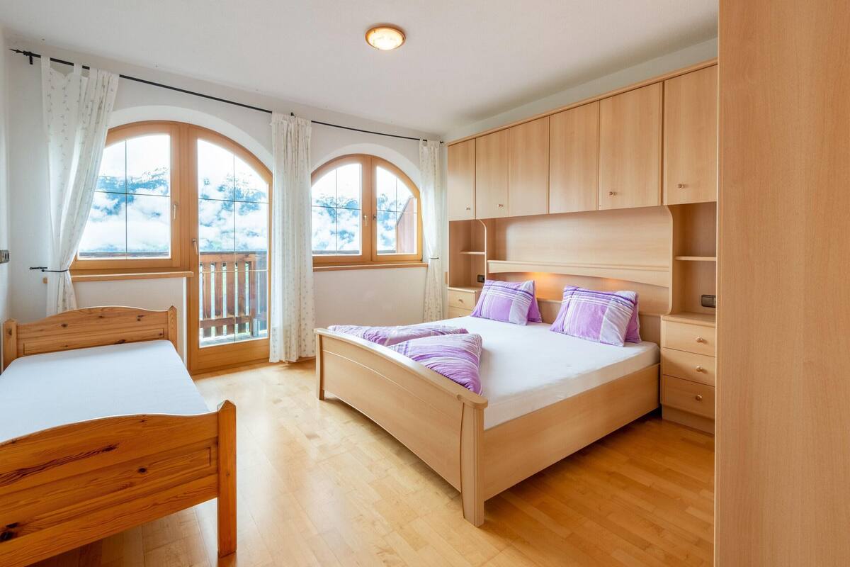 A bedroom with a wooden bed, a wooden desk, and a wardrobe.