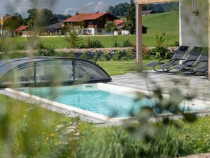 Relax by the serene pool surrounded by lush greenery and a wooden deck.