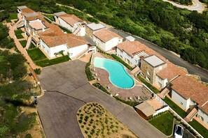 Una vista aerea di una zona residenziale con case, una piscina e un vialetto in pietra.