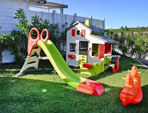 A children's play area with a slide, a small house, and a toy car. - Apartment in Golfo Aranci With Terrace (Arzachena)
