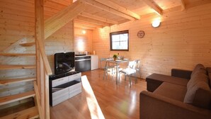 A cozy cabin with a wooden interior, a dining area with a table and chairs, a sofa, and a kitchen area with a stove and cabinets. - Year-round Holiday House With a Terrace, Near the Sea, Pustkowo (Rewal)