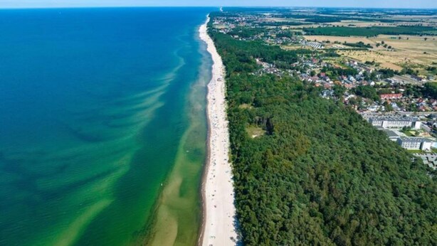 An aerial view of a coastal area with a long beach, dense forest, and residential buildings. - Year-round Holiday House With a Terrace, Near the Sea, Pustkowo (Rewal)