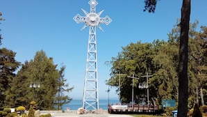 A tall metal cross structure with a base, surrounded by trees and a clear sky. - Year-round Holiday House With a Terrace, Near the Sea, Pustkowo (Rewal)
