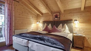 A wooden-paneled bedroom with a bed, two bedside lamps, and a radiator. - Chalets Almdorf Zillertal, Fugen (Fuegen)