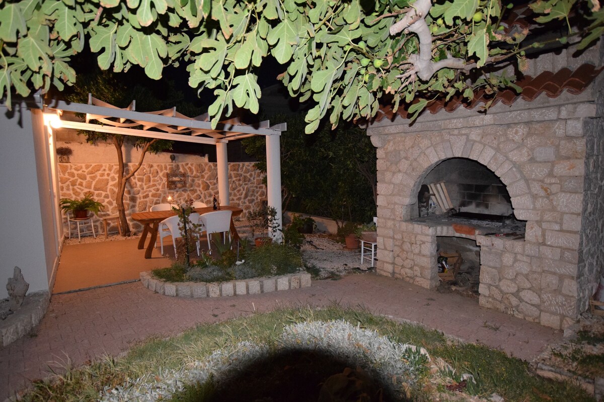 An outdoor patio with stone walls, a pergola, and a stone oven.