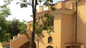 Ein zweistöckiges Gebäude mit flachem Dach, Rundbogenfenstern und einem Balkon.