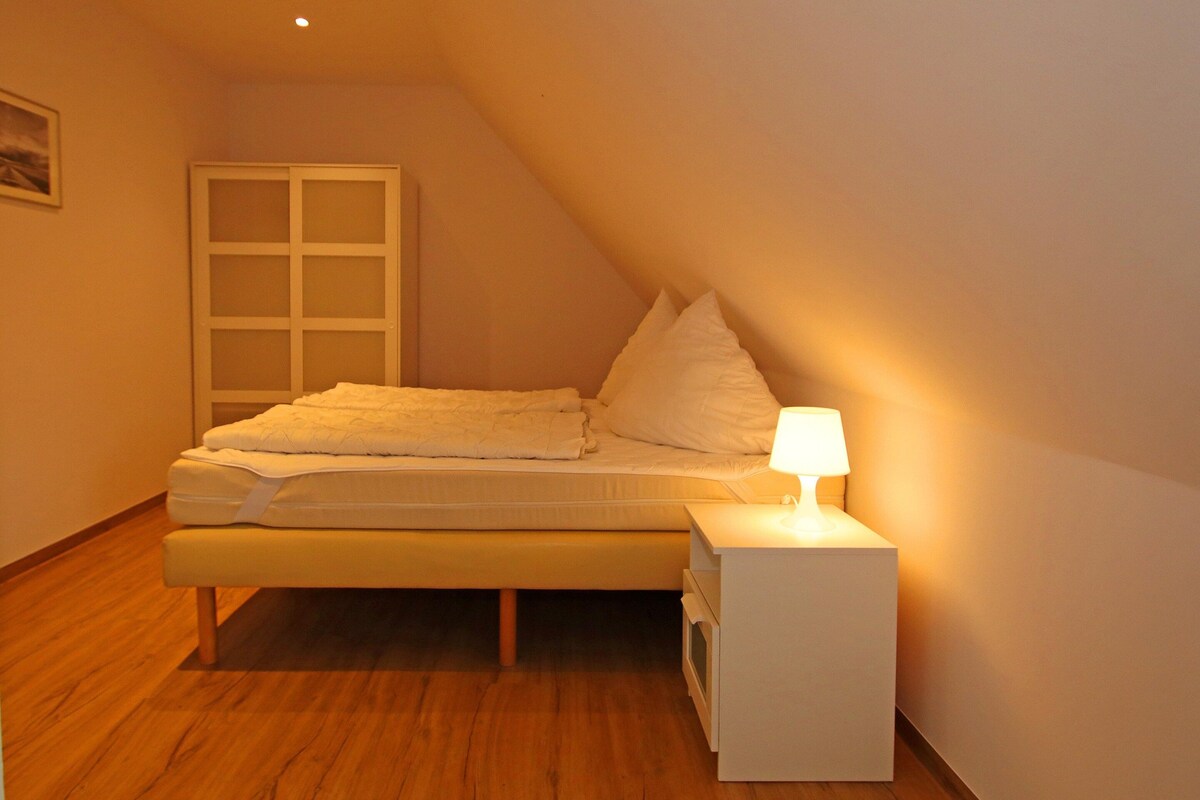 A bedroom with a bed, bedside table, and a nightstand.