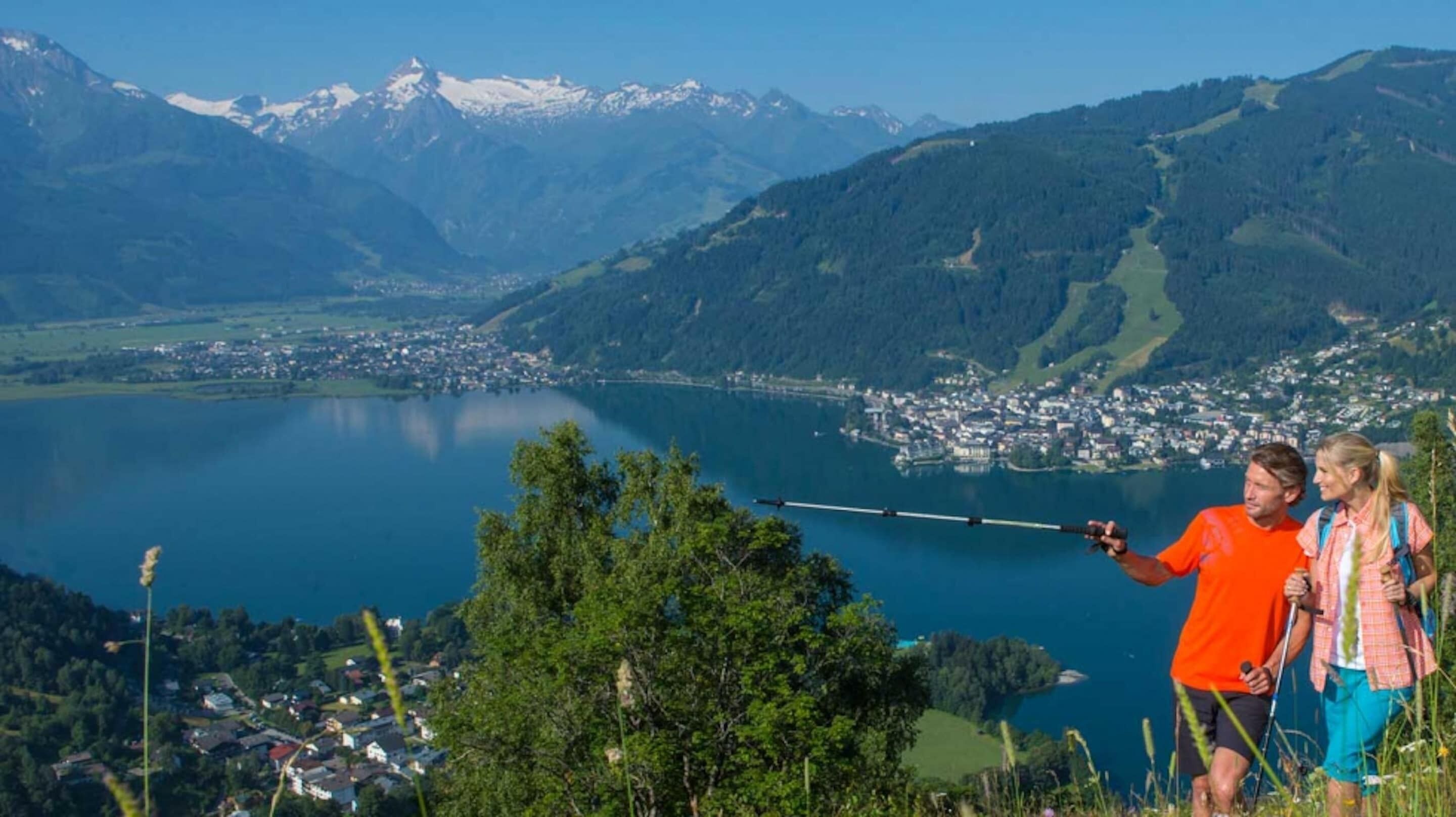Une vue panoramique d’un paysage montagneux, avec un lac, une petite ville et un ciel dégagé.