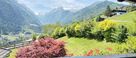 A view from a balcony overlooking a mountainous landscape with a village below.