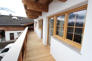 A balcony with wooden railings, large windows, and a view of neighboring buildings. - Modern Mansion in Kaprun Near Ski Area (Kaprun)