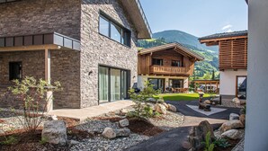 Une maison moderne avec une façade en pierre, de grandes fenêtres et une terrasse en bois.