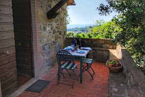 A stone wall with a table set for two, a basket of fruit, and a view of the countryside. - Cozy Farmhouse in Paciano With Private Pool (Paciano)