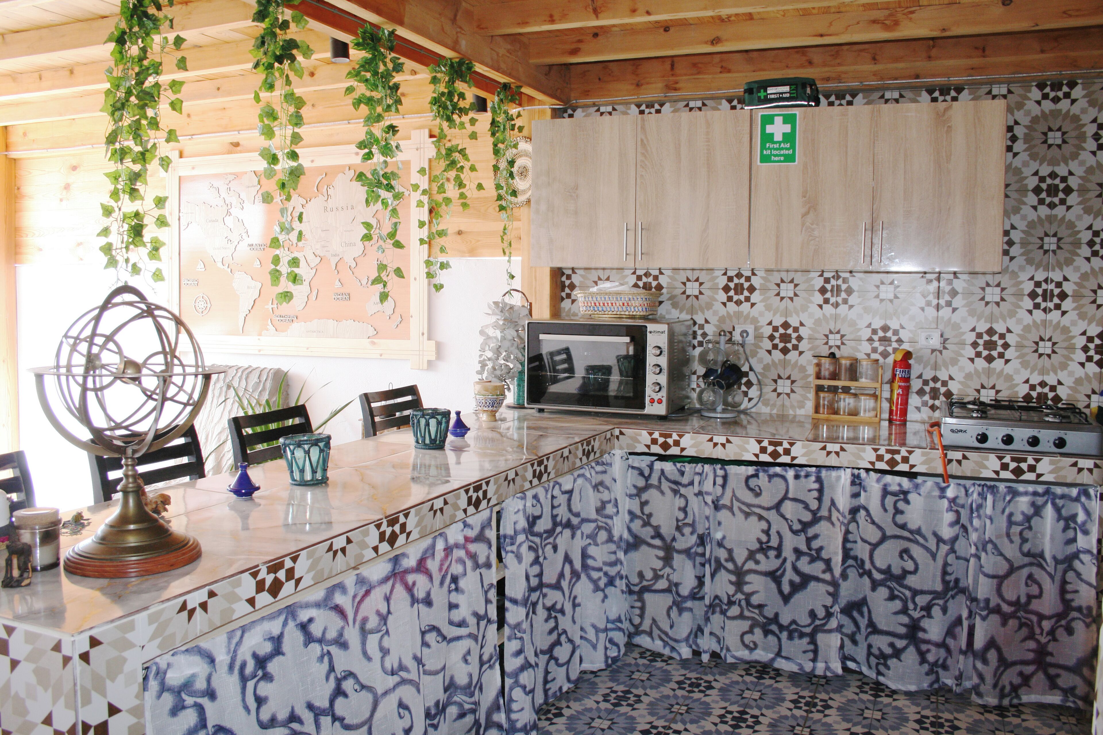 A kitchen with a wooden ceiling, a map on the wall, cabinets, a microwave, and a stove.