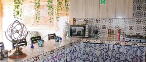 A kitchen with a wooden ceiling, a map on the wall, cabinets, a microwave, and a stove.