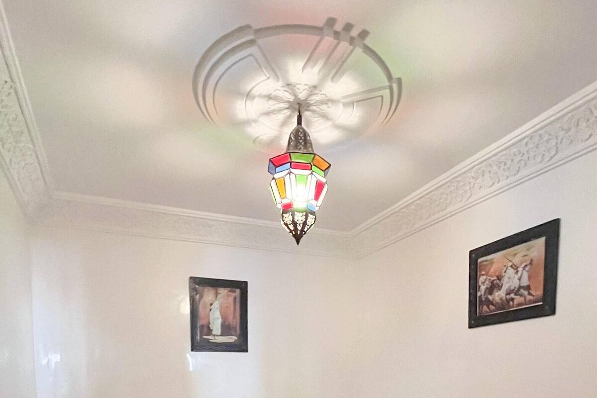 Une chambre d’hôtel avec un lit, un lustre coloré et un tapis à motifs.