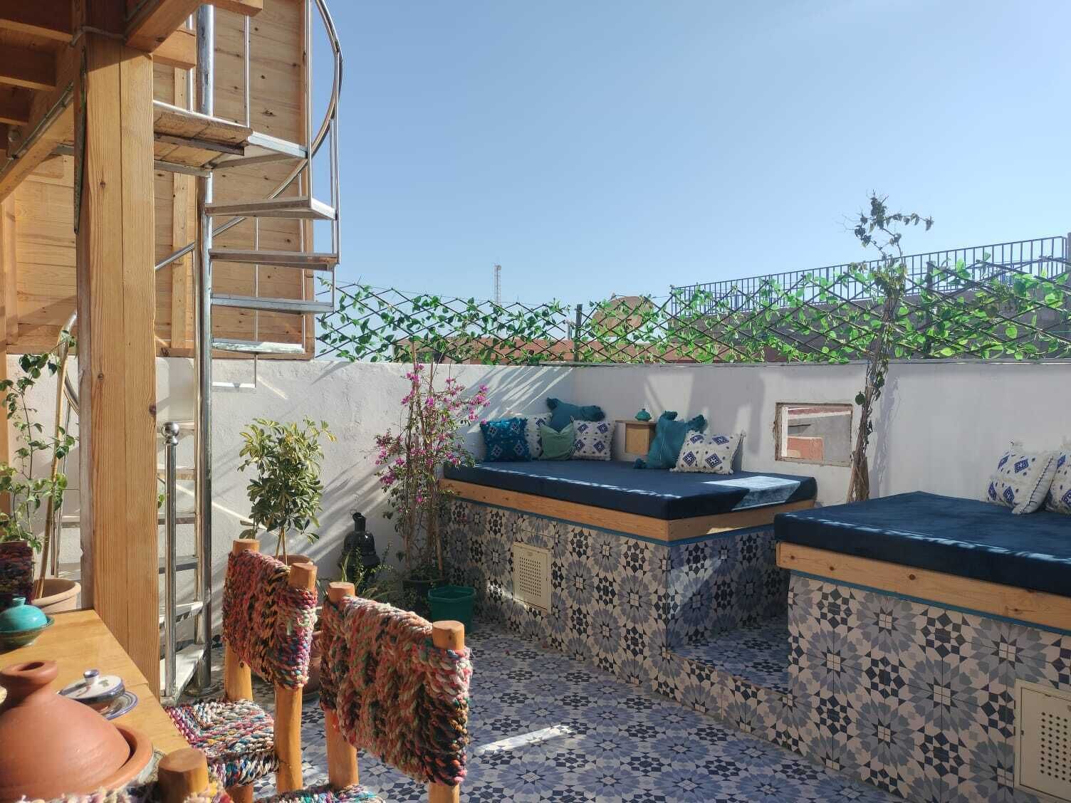 Une terrasse sur le toit, dotée d’un espace salon, d’un escalier en bois et offrant une vue sur le paysage urbain.