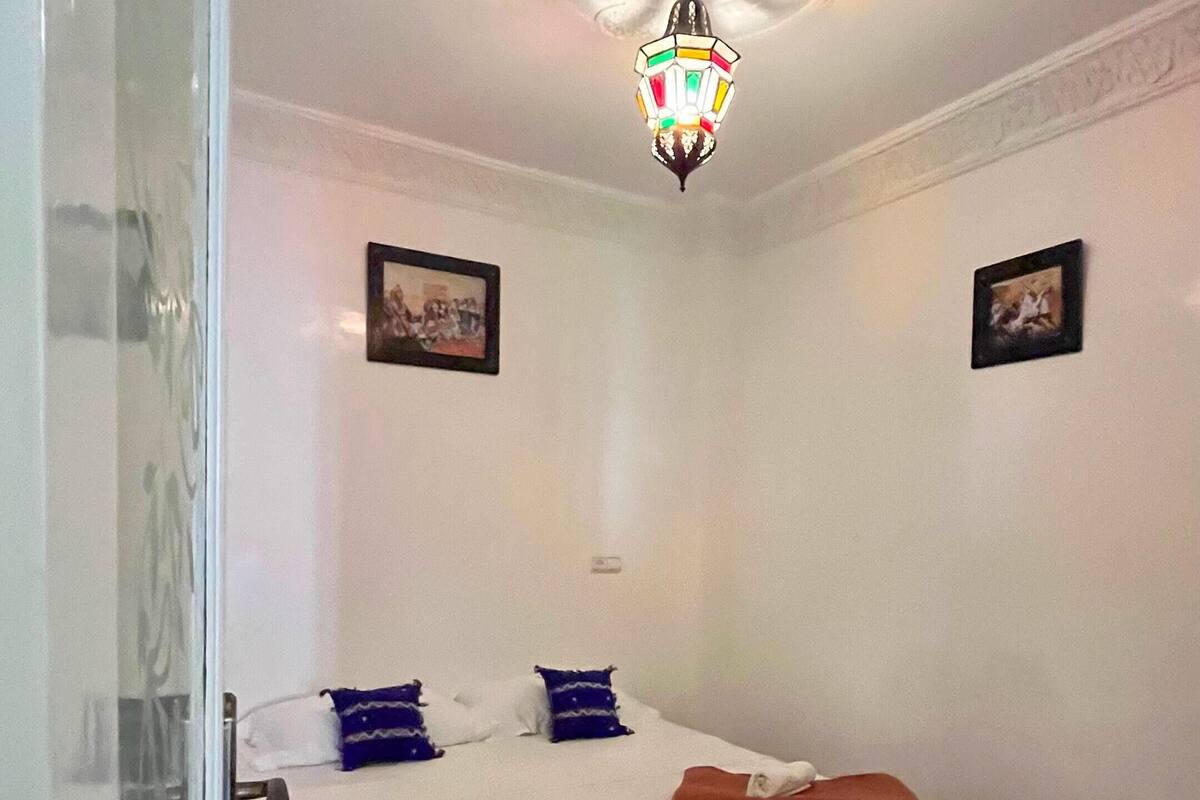 Une chambre d’hôtel avec un lit, un tapis à motifs et un lustre.