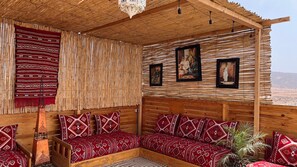 A room with a wooden ceiling, bamboo wall panels, and a wooden bed with patterned pillows. There are two framed pictures on the wall. - Aourir Waves Surf House (Aourir)