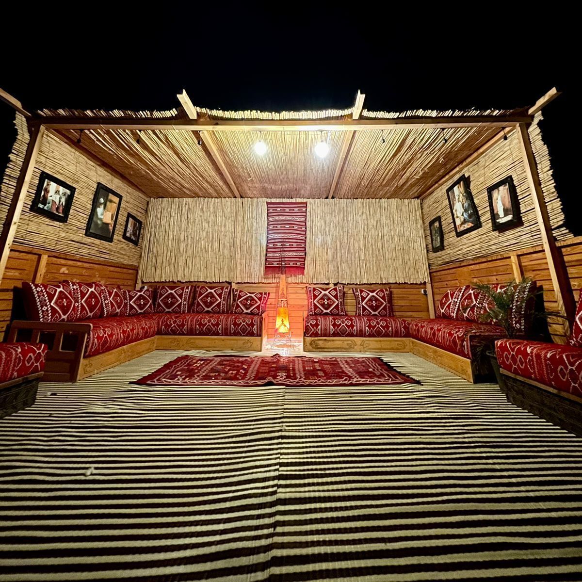 Una habitación acogedora y luminosa, con chimenea central, paredes de madera y cojines estampados.