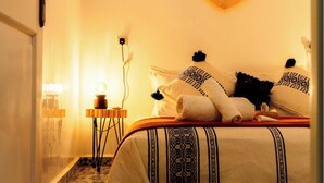 Un dormitorio con colcha estampada, un adorno en forma de corazón y alfombra con diseño.