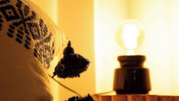 A bed with a patterned pillow and a small table with a light bulb.