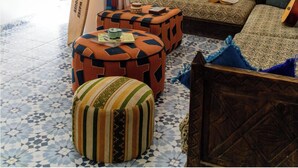 Una habitación con piso estampado, un sofá con cojines, una cama de madera y una tabla de surf apoyada contra la pared.