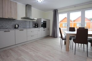 A modern kitchen with granite countertops, stainless steel appliances, and a dining area with a table and chairs. - Apartment Hafenflair am Plauer See, Plau am See (Plau am See)