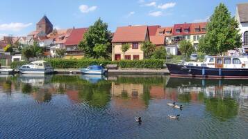 A calm river with boats and ducks, surrounded by traditional houses with red roofs.