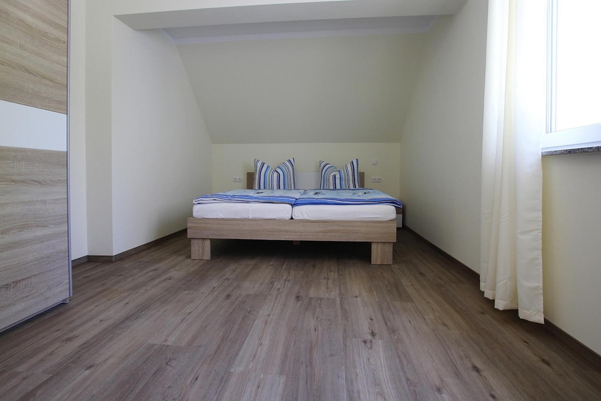 A bedroom with a wooden bed, white walls, and a sloped ceiling.