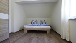 A bedroom with a wooden bed, white walls, and a sloped ceiling. - Apartment Hafenflair am Plauer See, Plau am See (Plau am See)