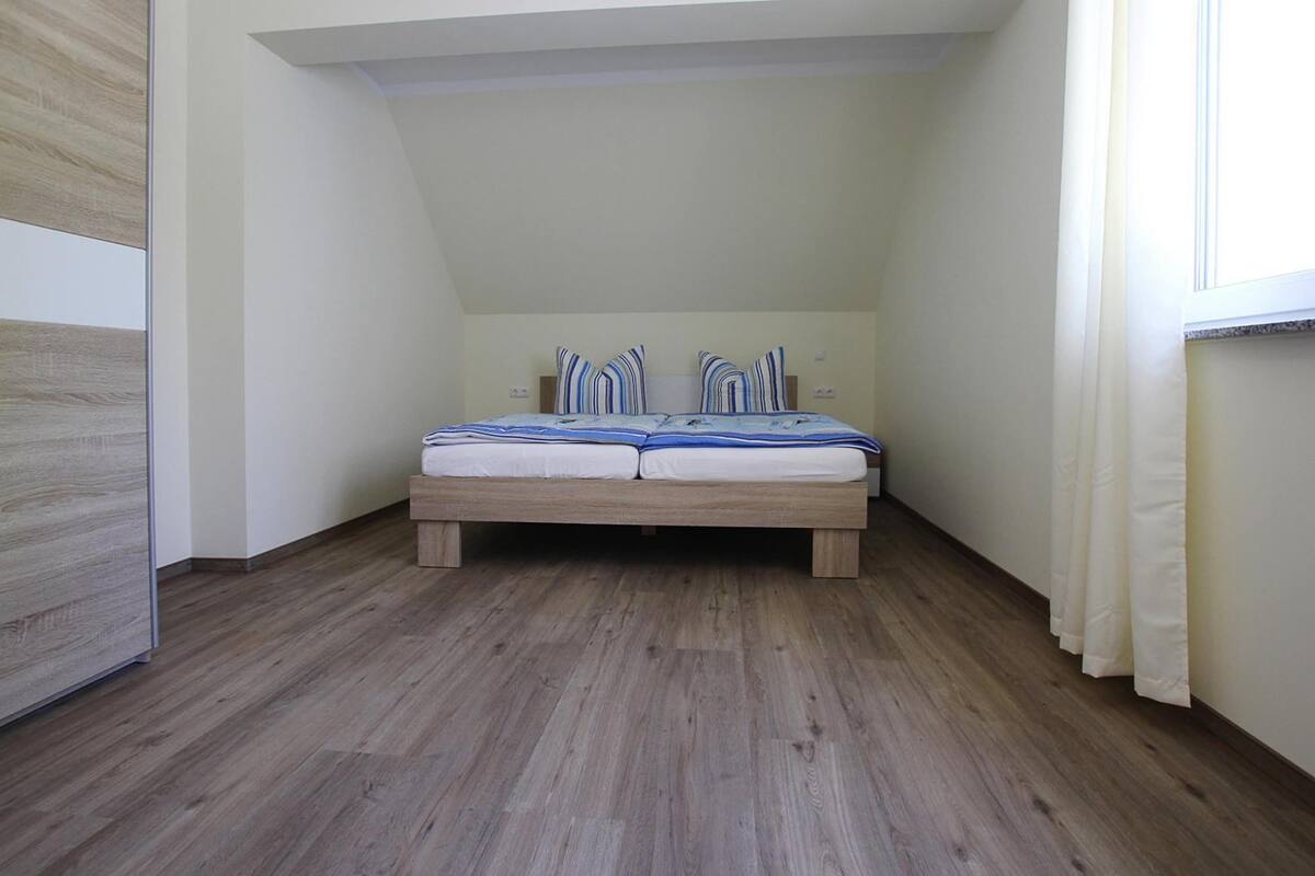 A bedroom with a wooden bed, white walls, and a sloped ceiling.