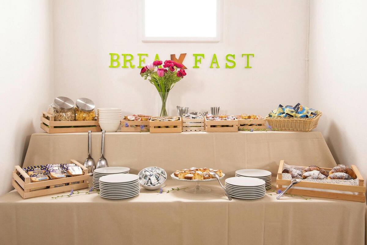 A breakfast buffet setup with various food items and utensils.