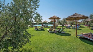 A poolside area with lounge chairs and umbrellas, a swimming pool, and a well-maintained lawn. - Residence Le Corti di Montepitti, Suvereto (Suvereto)