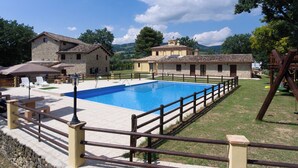 Una piscina rodeada por una cerca de madera, con edificios de piedra al fondo.
