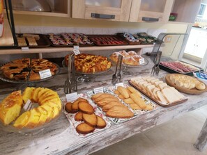 A variety of baked goods displayed on a marble countertop in a bakery setting. - Borgo Pratole Country House (Cingoli)