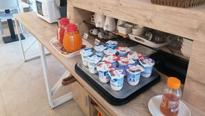 Una barra de desayuno con vasos de yogur, zumo y una cesta.